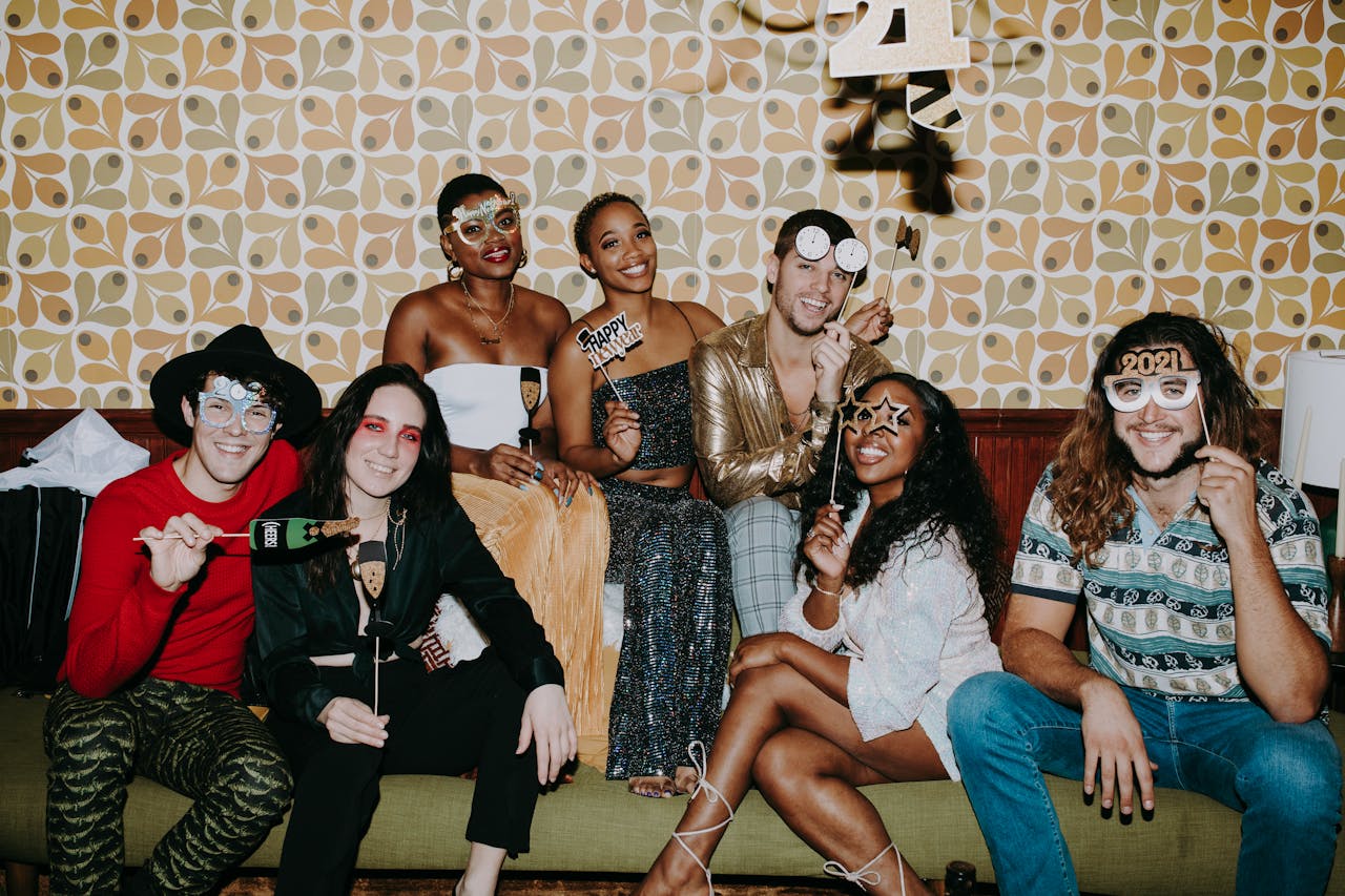 Group of friends celebrating New Year's Eve with fun props and festive attire indoors.